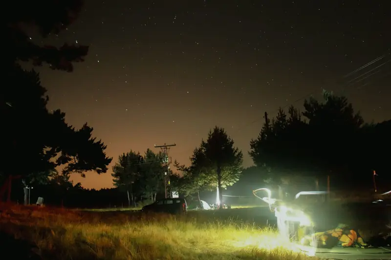 A serene night camping scene with tents under a starry sky in a forest setting