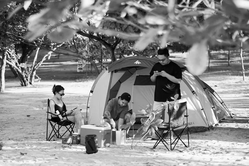 A group enjoying a camping trip with a tent set up in a sandy outdoor area