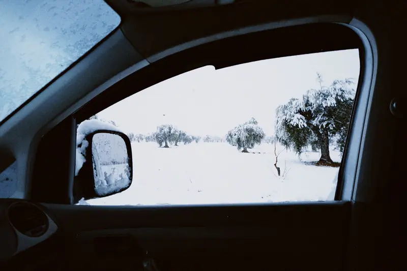 A serene snowy landscape seen from a car interior, capturing winter's beauty through a side window